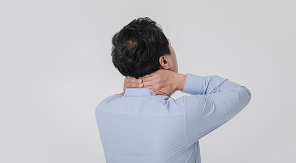 침대에 앉아 머리를 짚고 있는 사람